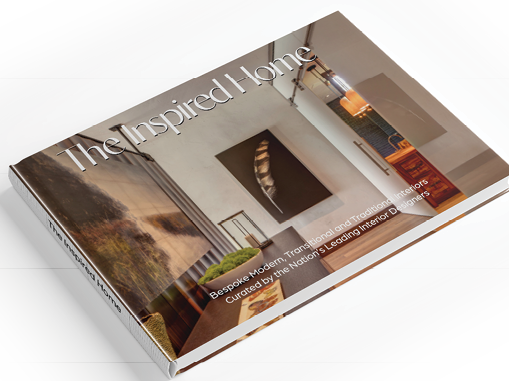 The Inspired Home, a hardcover book photographed flat, its cover showing a modern interior with a feather artwork, stone wall and warm timber joinery.